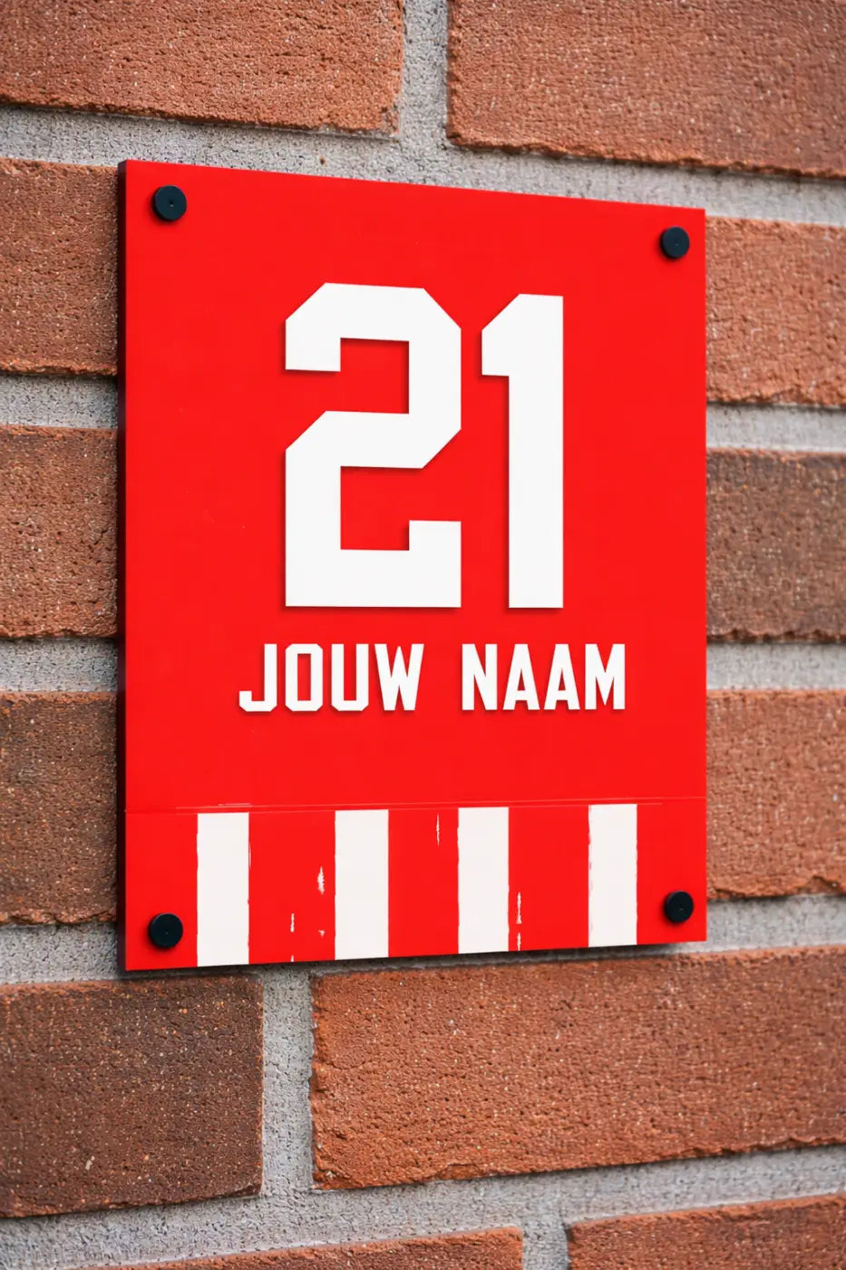 Rood rechthoekig naambordje voordeur met witte cijfers 21 en tekst jouw naam gemonteerd op bakstenen muur voetbal eindhoven